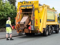 Brown wheeled bin being emptied into a lorry, with a man in a high vis vest watching from behind the lorry