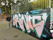 Man stood by a skate park ramp with a graffiti design on it