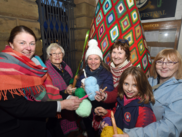 group of ladies with crochet equipment stood in front of a crocheted Christmas tree