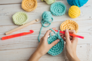 Hands using a crochet hook to make a blue circle