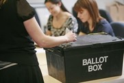 Black ballot box with a hand posting a ballot paper in it