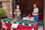 Two woman stood behind a table selling different varieties of cherries