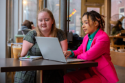 Two woman sat at cafe using a laptop