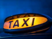Close up of orange lit taxi sign on top of cab.