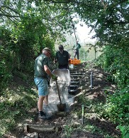 Two men fixing some steps in a wooded area