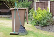Brown bin with garden waste, rake leaning against it