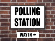 Brick wall with a sign saying 'polling station - way in' on it.