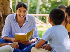 Woman reading a book to group of children.