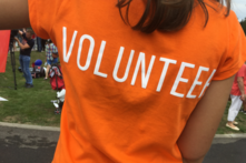 Back of person in an orange tshirt which say volunteer on.