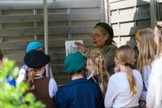 elder lady dressed in war time clothing talking to a group of children