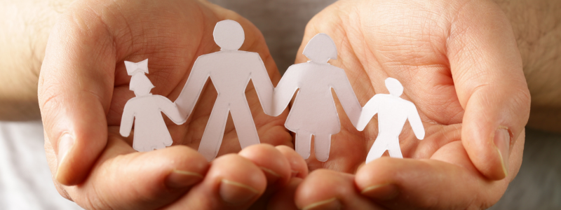 A pair of hands holding a cut-out of a family