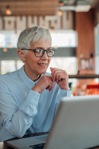 A woman with short grey hair sits at a laptop