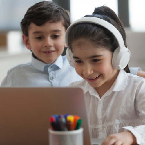 Two young children look at a laptop