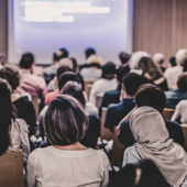 A room of people watching a presentation in a meeting room