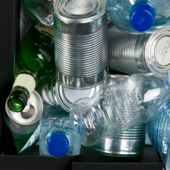 A recycling box filled with items including plastic bottles, tin cans and glass bottles