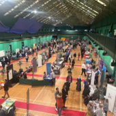 A large sports hall filled with stalls and banners for local employers