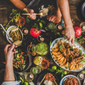 People reach over a table filled with food to share portions