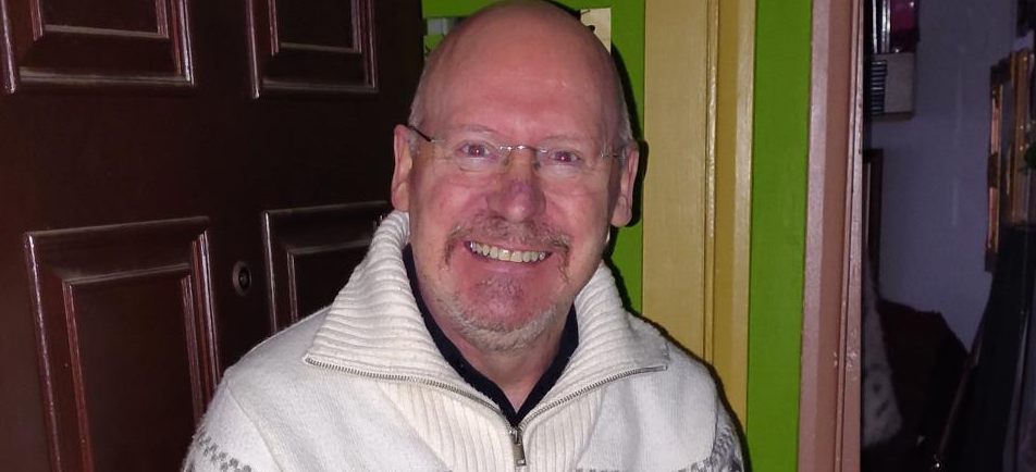 Smiling man in cream jumper at his open door