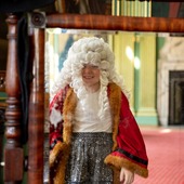 A girl looking into a mirror wearing a wig and gown 