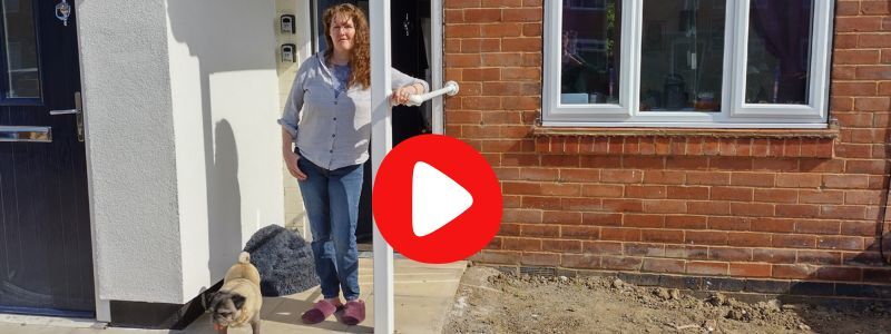 A woman and her small dog stand at a front door of a flat