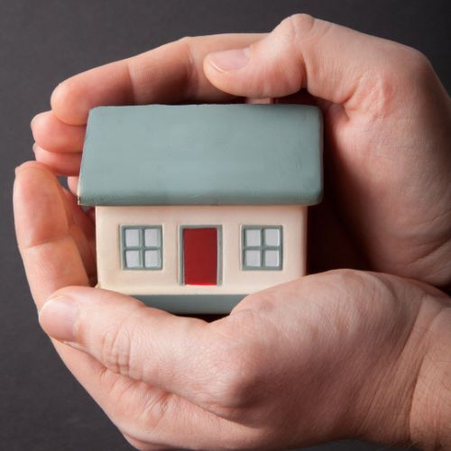 A pair of hands cradle a model of a house