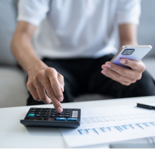 Man works with paper, a calculator and phone