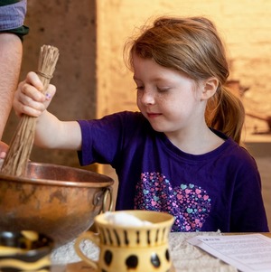 Girl in stirring a bowl in historic kitchen