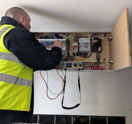 A man in a high-vis jacket fixing a fuse box