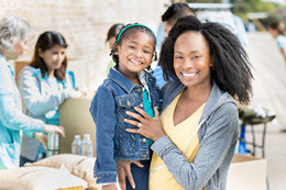 African American mom and her preschool age girl at a community drive.
