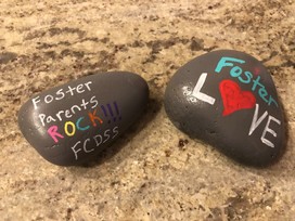 Two painted rocks that say "Foster Parent Rock FCDSS!!" and "Foster Love"