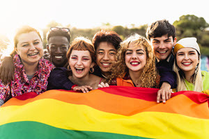 Diverse group of teenagers standing behind Pride flag