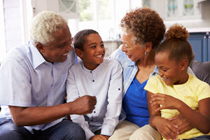 Grandparents and their young grandchildren relaxing at home.