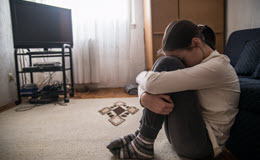 Teen woman with headache holding her head in her living room during the day