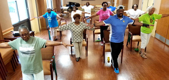 Group of seniors with arms stretch out doing falls prevention exercise