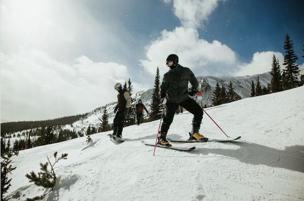 Image of individuals on a snow-covered peak wearing skis and cold weather gear