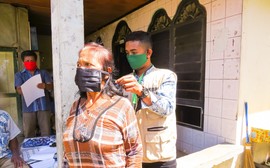 Kopi Nande project staff assist one of project's beneficiaries with her face mask in Indonesia. 