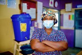 Midwife stands resolutely while wearing face mask. 