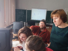 Partners from northern Ukraine share information about the project with community members around a computer. A man in the back points to the screen.