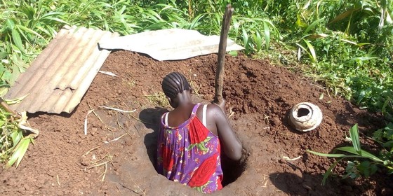 Rose Ukure digs a pit latrine in her compound