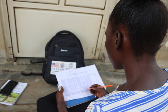 Linda, a community outreach volunteer, reads through a list of clients due for HIV viral load testing. Photo: IntraHealth International