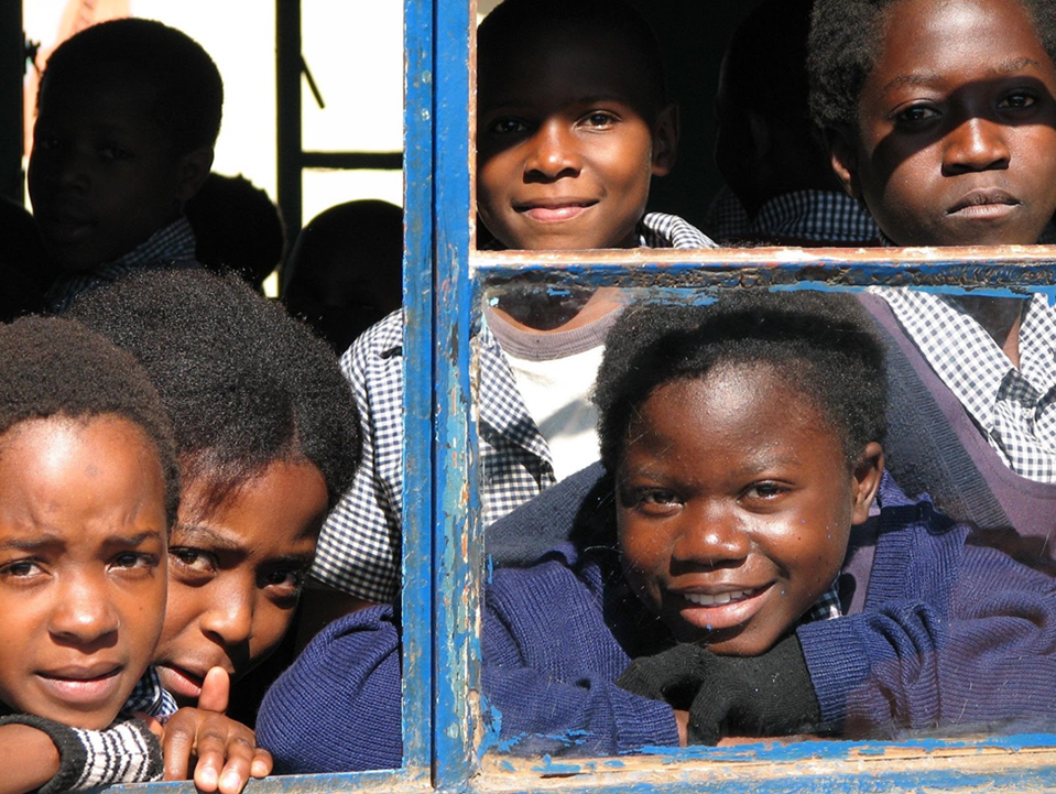 Students look out a classroom window at Regiment Basic School in Lusaka, Zambia