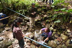 Water association members measure the flow of water at their community water source.