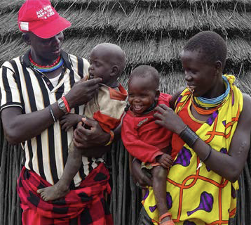 Father and mother each hold a child in their arms smiling 