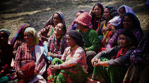 Women in a remote village in Nepal gather under the shade of a pine tree to escape the heat and share their life experiences with USAID.