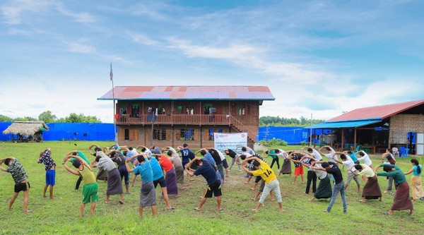 In Burma's Kachin State, a group stretches arms in a field as part of a rehabilitation program's morning exercise.
