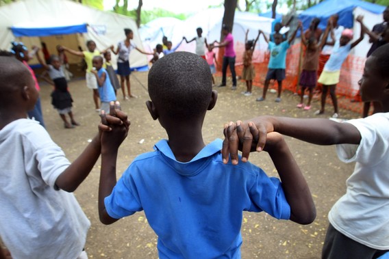 Back of a child's head while they stand in a circle holding hands with a group of children