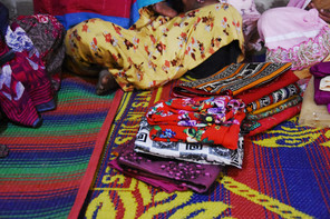 Bright fabrics with multiple patterns are spread on the ground.