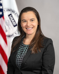 A woman in a suit smiles at the camera.