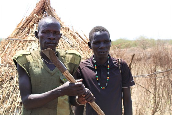 Lowilo Lokeita (left) displays a tool he used to build a pit latrine at his home in Kapoeta North County 