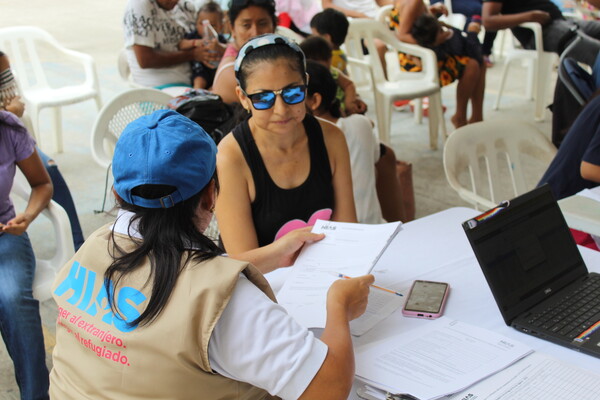 HIAS team member speaks to community member at multi-purpose cash assistance distribution center 